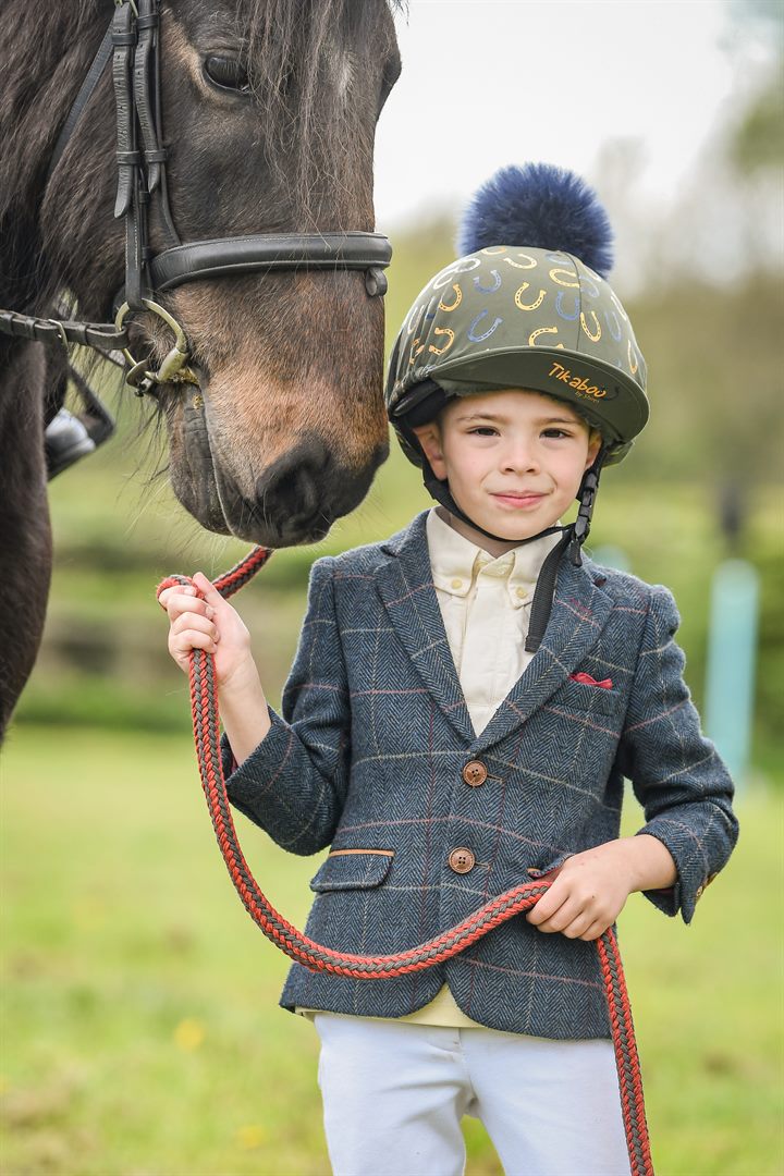 A young club member standing beside a dark horse